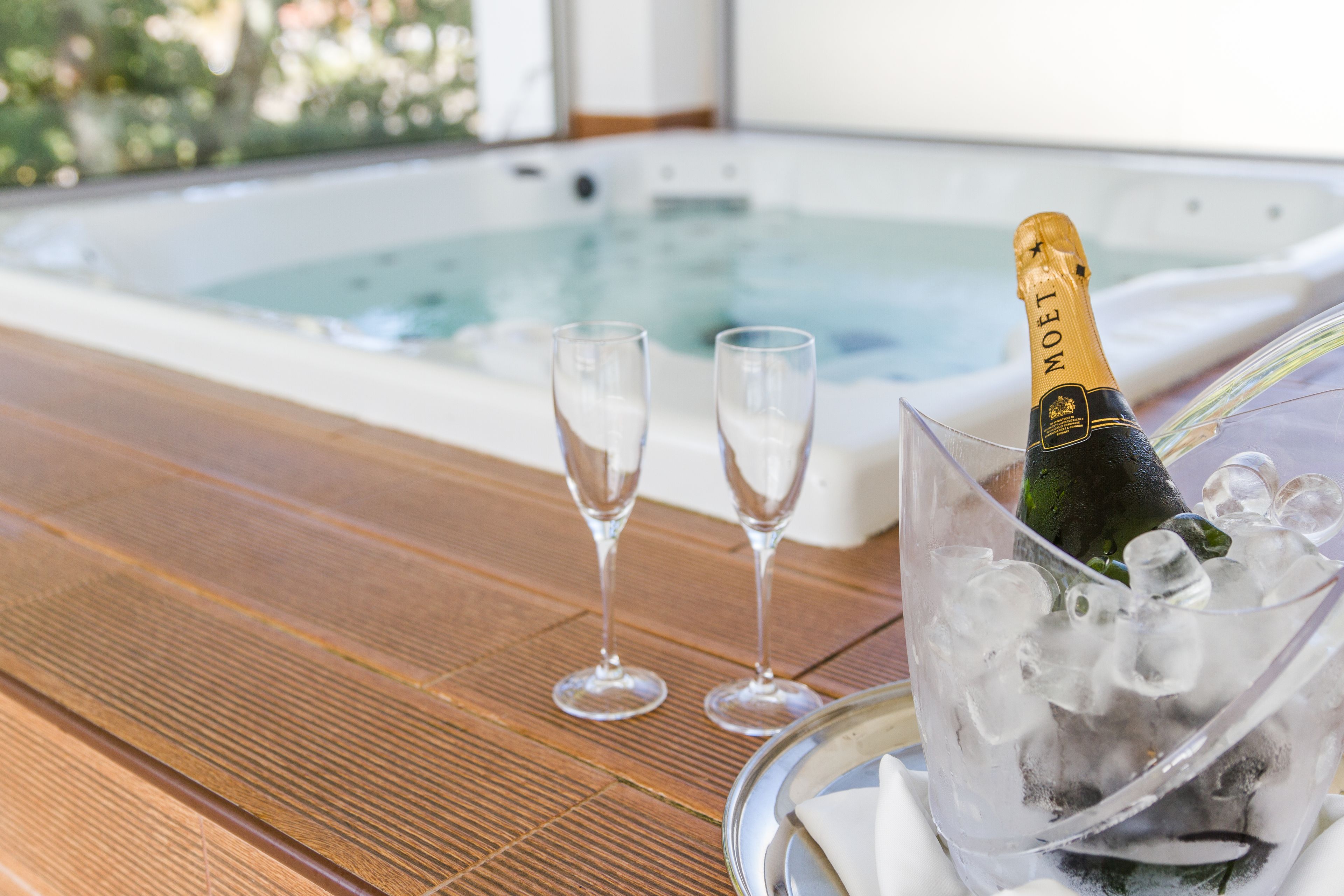 Una botella de Moët champagne en un vaso con cubitos de hielo sobre una mesa de madera, junto a dos copas vacías.