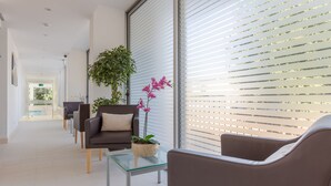 A modern waiting area with a sofa, chairs, a glass table, and a potted plant.