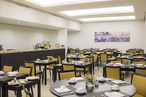 Formal dining area with tables set for service, featuring white tableware and elegant seating.