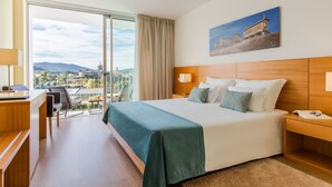 A hotel room with a large bed, a desk, and a view of a cityscape.