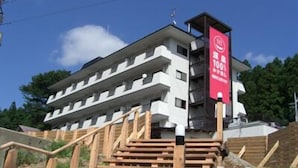 A multi-story building with a white facade and a red banner. - Kinugawa Niouson Plaza (Nikko)