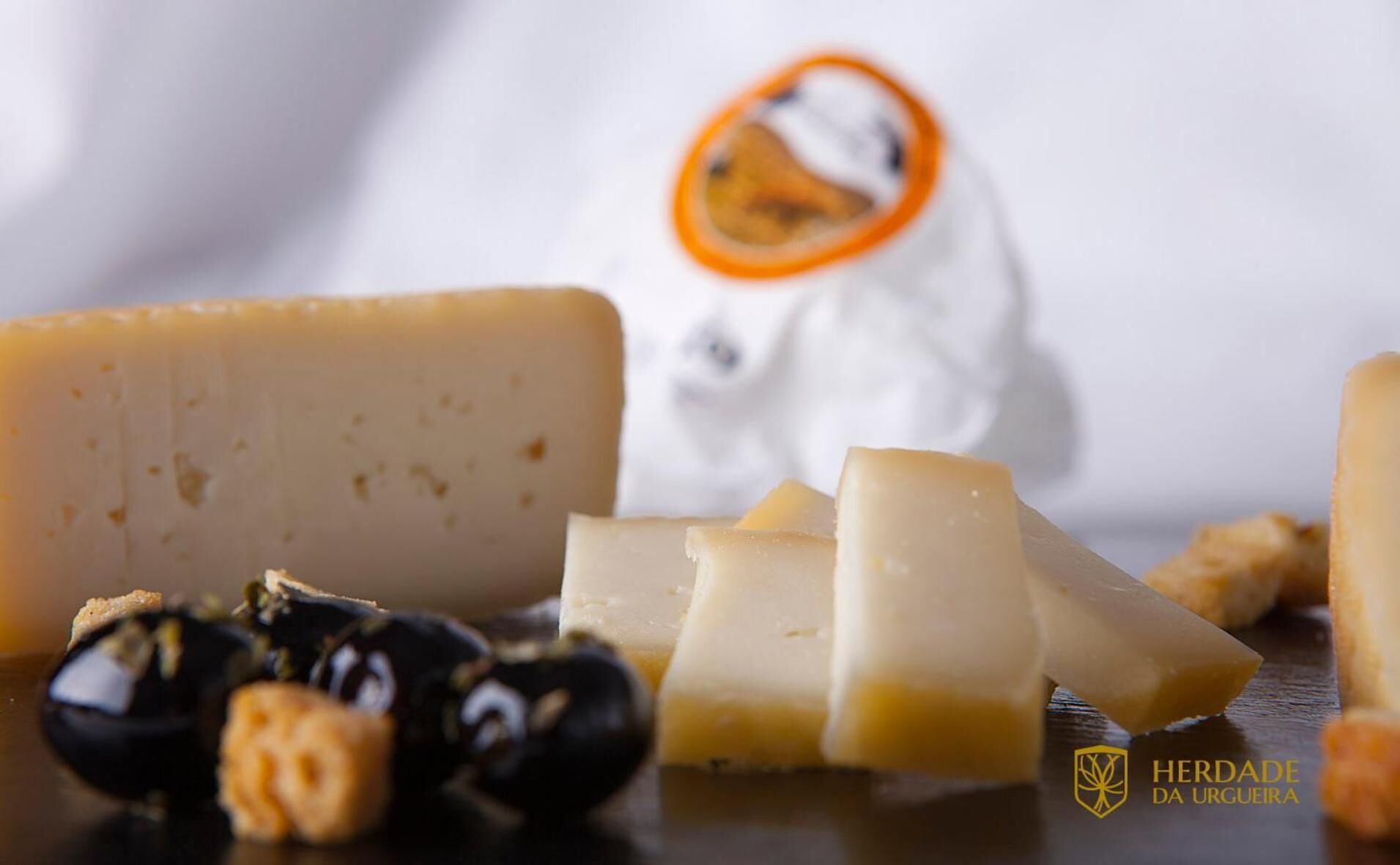 A variety of cheeses and olives on a wooden surface.