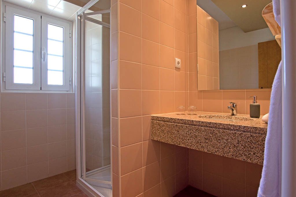 A bathroom with a shower, a sink with a granite countertop, and a mirror.