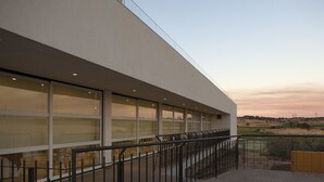 A modern building with large windows, a flat roof, and a wooden deck. - Herdade da Urgueira (Vila Velha de Rodao)