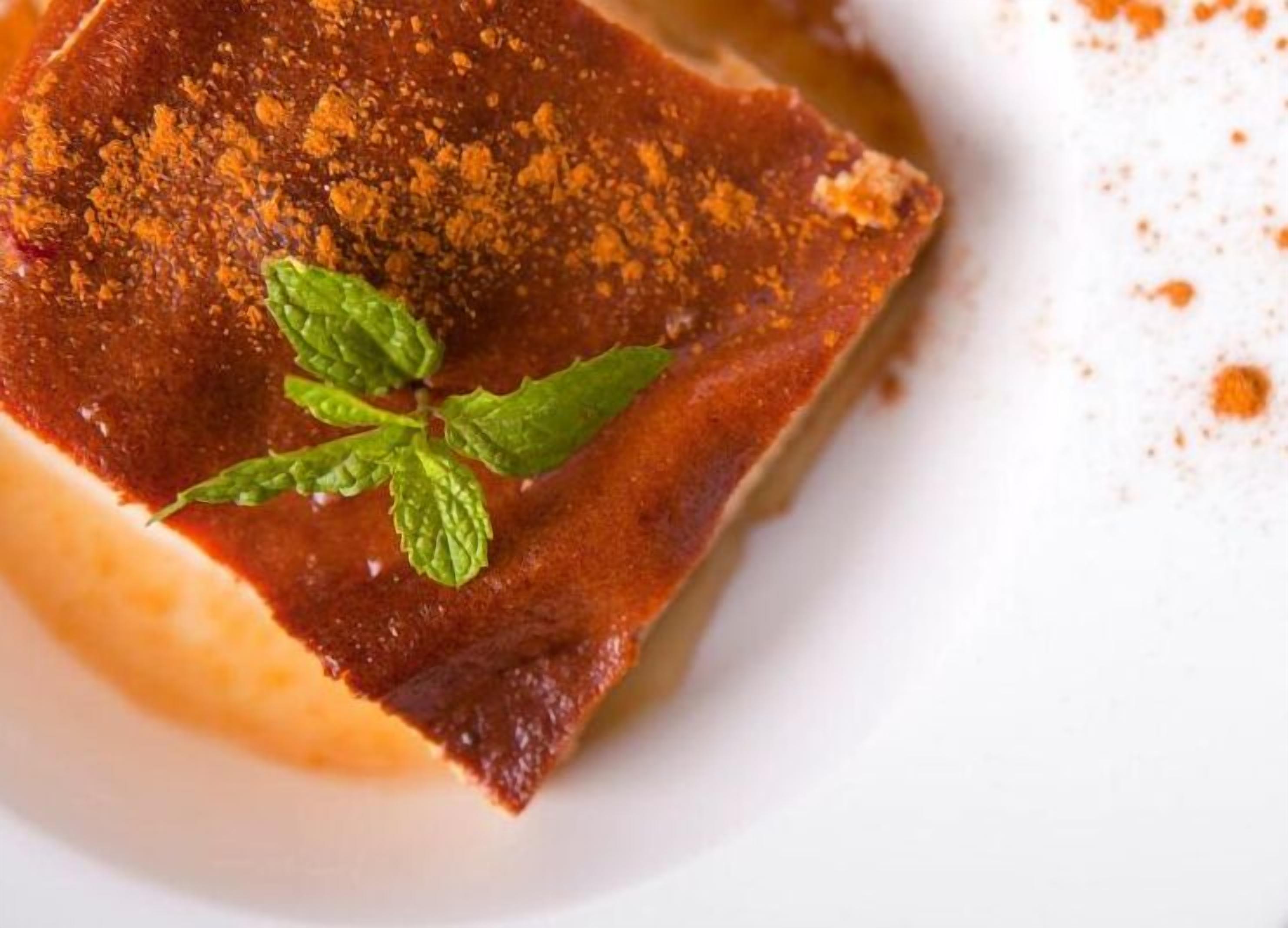 Un dessert à la croûte dorée, garni d’une feuille de menthe et servi dans une assiette blanche.