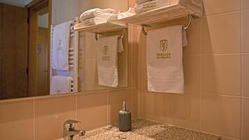 A bathroom with a granite countertop, a sink, and a mirror. There are towels hanging on a rack above the sink, each with a logo.