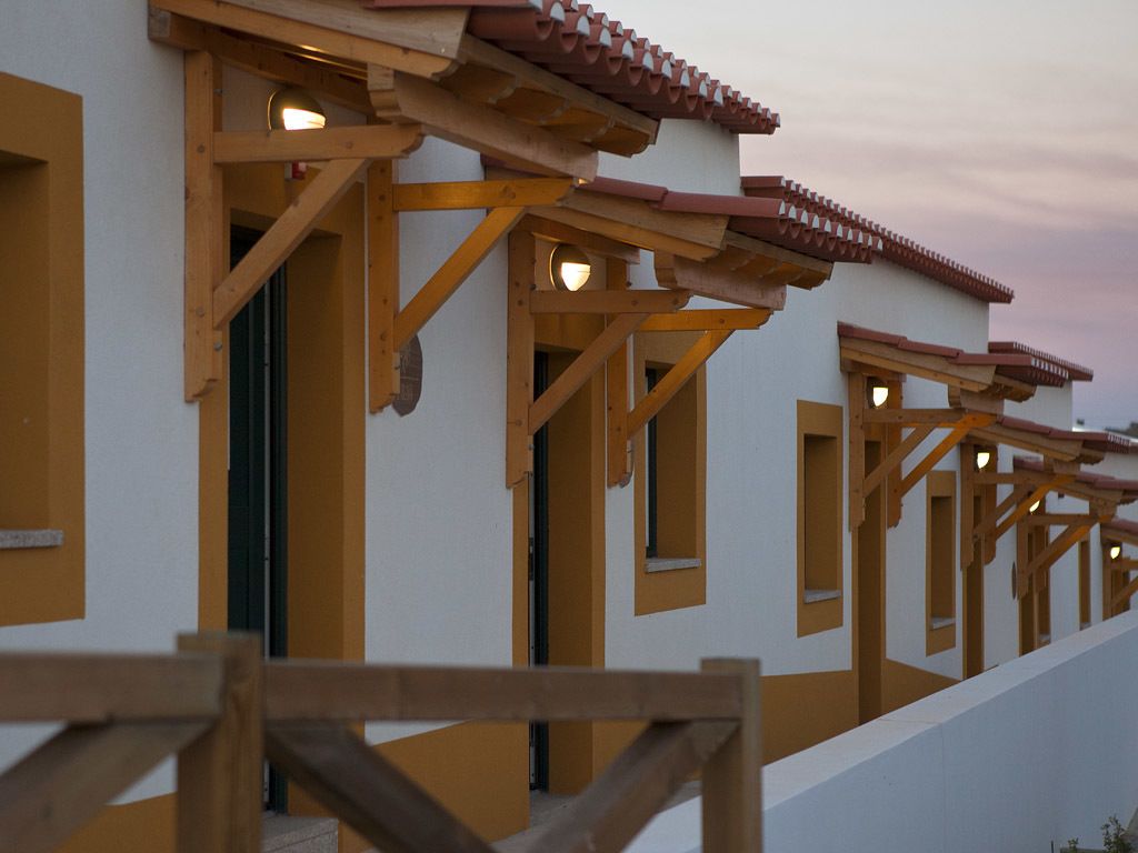 Una hilera de habitaciones de hotel con balcones de madera y paredes blancas.