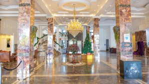 A grand lobby with a chandelier, marble columns, a Christmas tree, and a reception desk. - Weston Hotel (Nairobi)