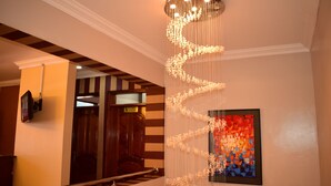 A staircase with a handrail, a wall-mounted artwork, and a ceiling light fixture. - Weston Hotel (Nairobi)