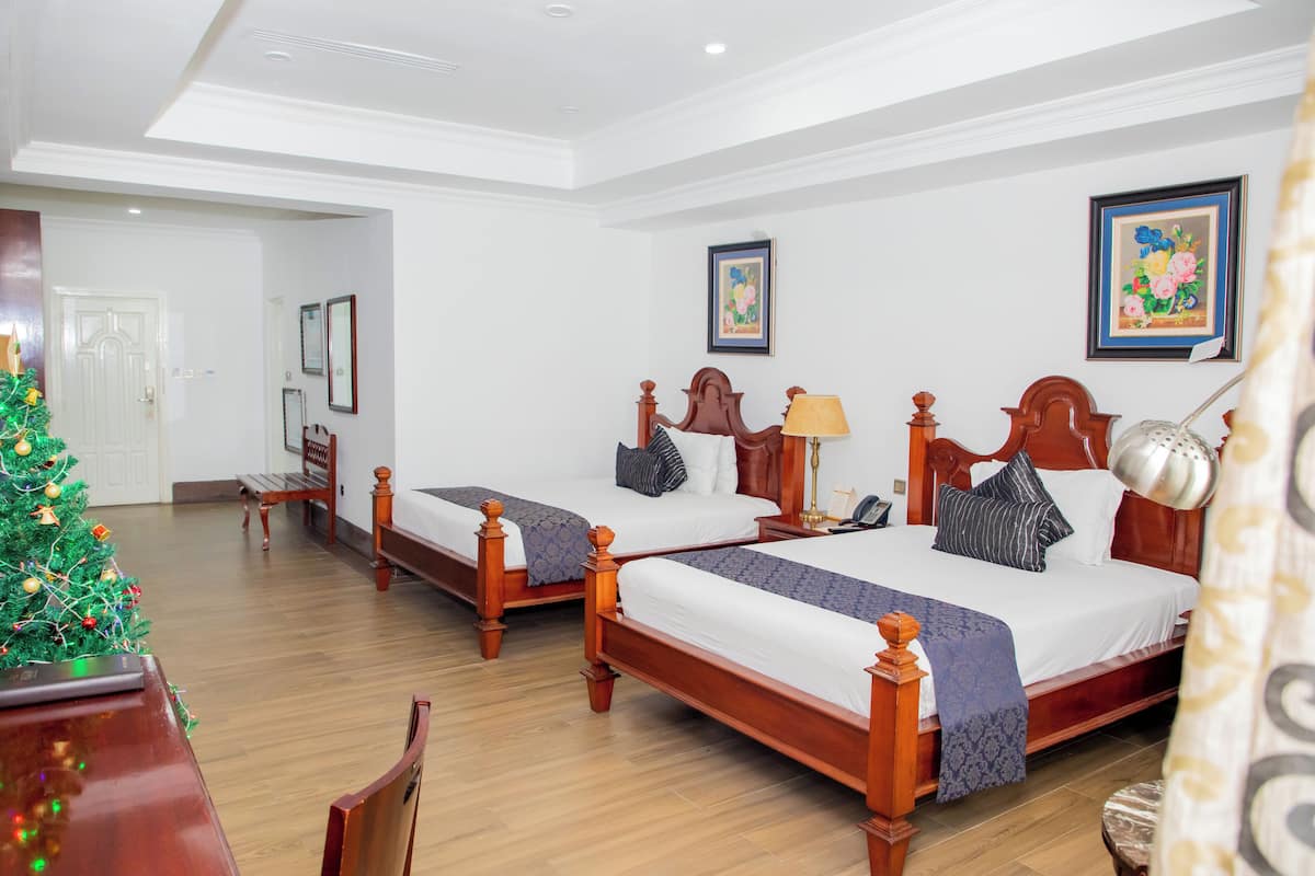 Una habitación de hotel con dos camas de madera, un árbol de Navidad y un escritorio de madera.