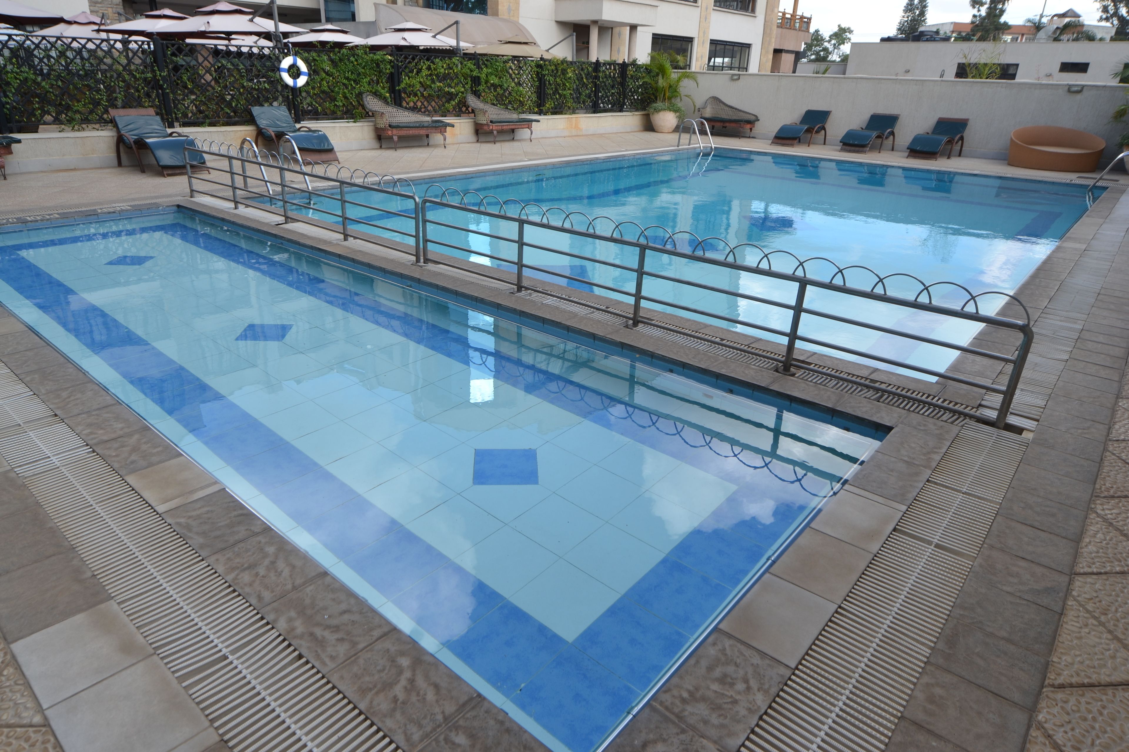 Una piscina al aire libre, sombrillas, sillones reclinables de piscina