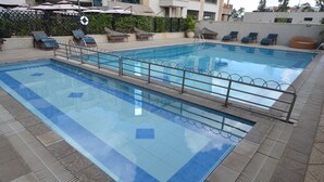A rectangular swimming pool with a metal safety railing, surrounded by lounge chairs and umbrellas. - Weston Hotel (Nairobi)