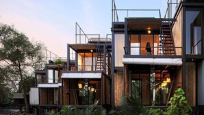 A modern multi-story building with open balconies and large windows, featuring a mix of wooden and metal materials. - Bangkok Tree House (Phra Pradaeng)