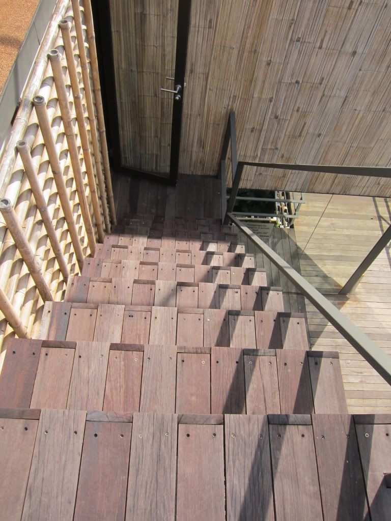 Una escalera de madera que conduce a una puerta con marco metálico.