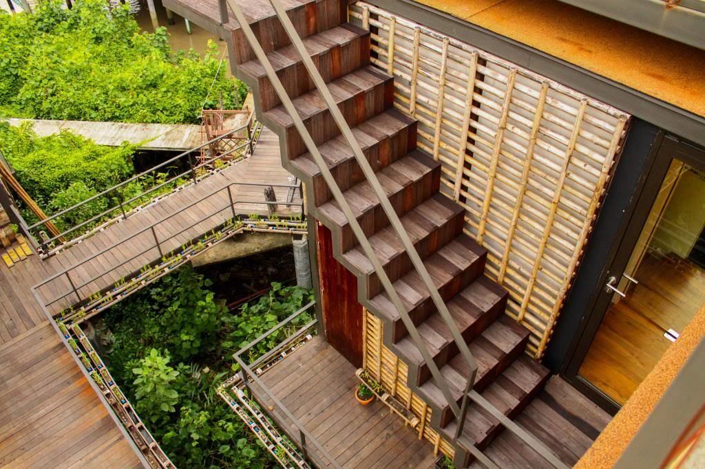 A multi-level wooden staircase with a metal railing, surrounded by lush greenery.