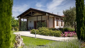 A building with a covered patio, surrounded by well-maintained gardens and a gravel path.