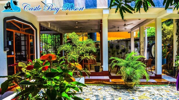 Un patio con plantas en macetas, suelo de baldosas y un letrero que dice "Castle Bay Resort".