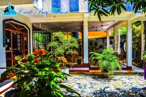 A courtyard with potted plants, a tiled floor, and a sign reading "Castle Bay Resort". - Castle Bay Resort (Weligama)