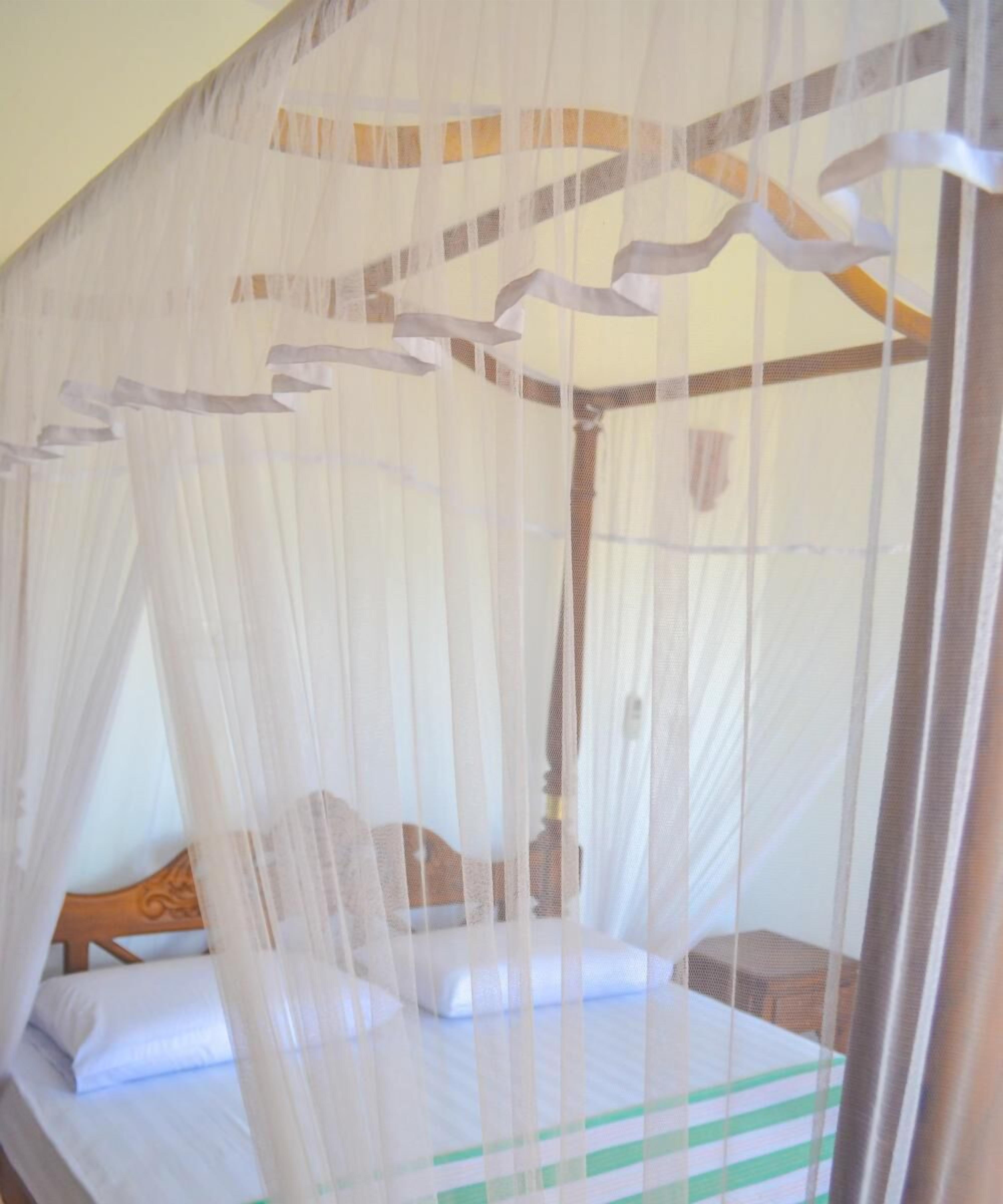 A bed with a canopy, a wooden headboard, and a bedside table.