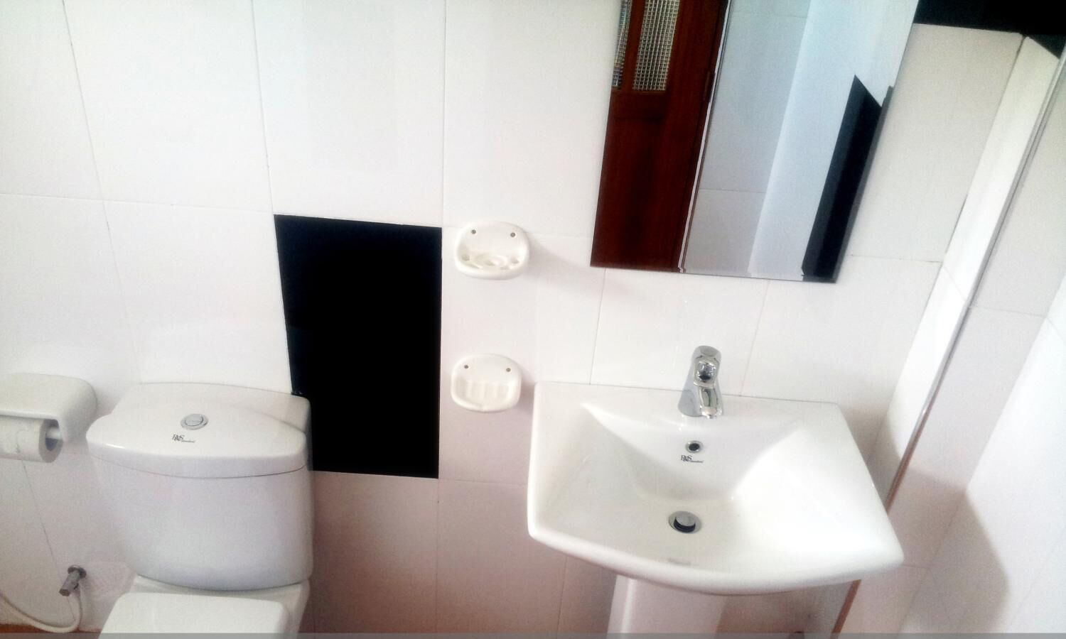 Une salle de bain avec des toilettes, un lavabo et un miroir.