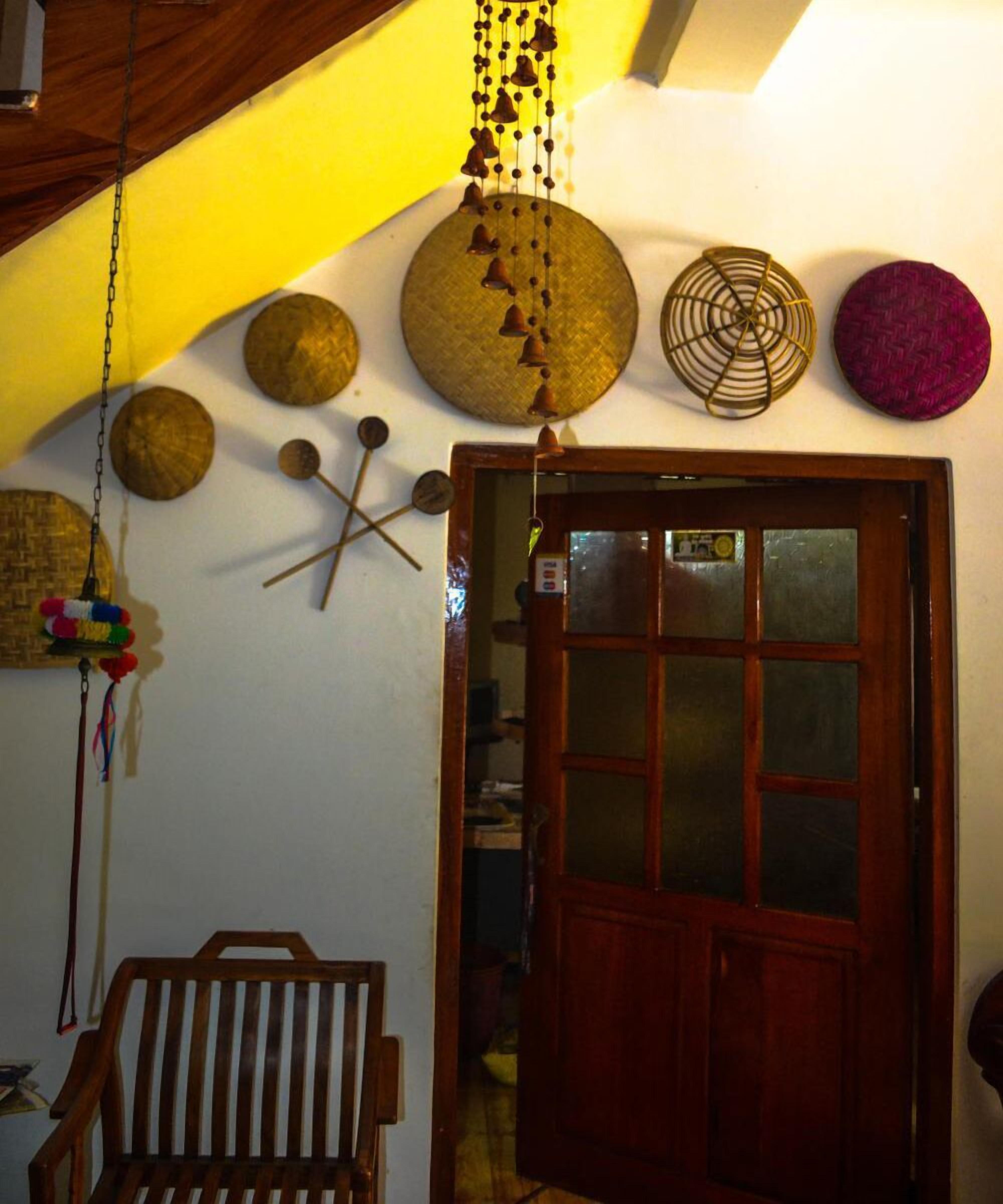Una habitación con una puerta de madera, una campana colgante y una cesta tejida.