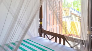 Una habitación con cama con dosel, ventilador de techo y vistas al exterior.
