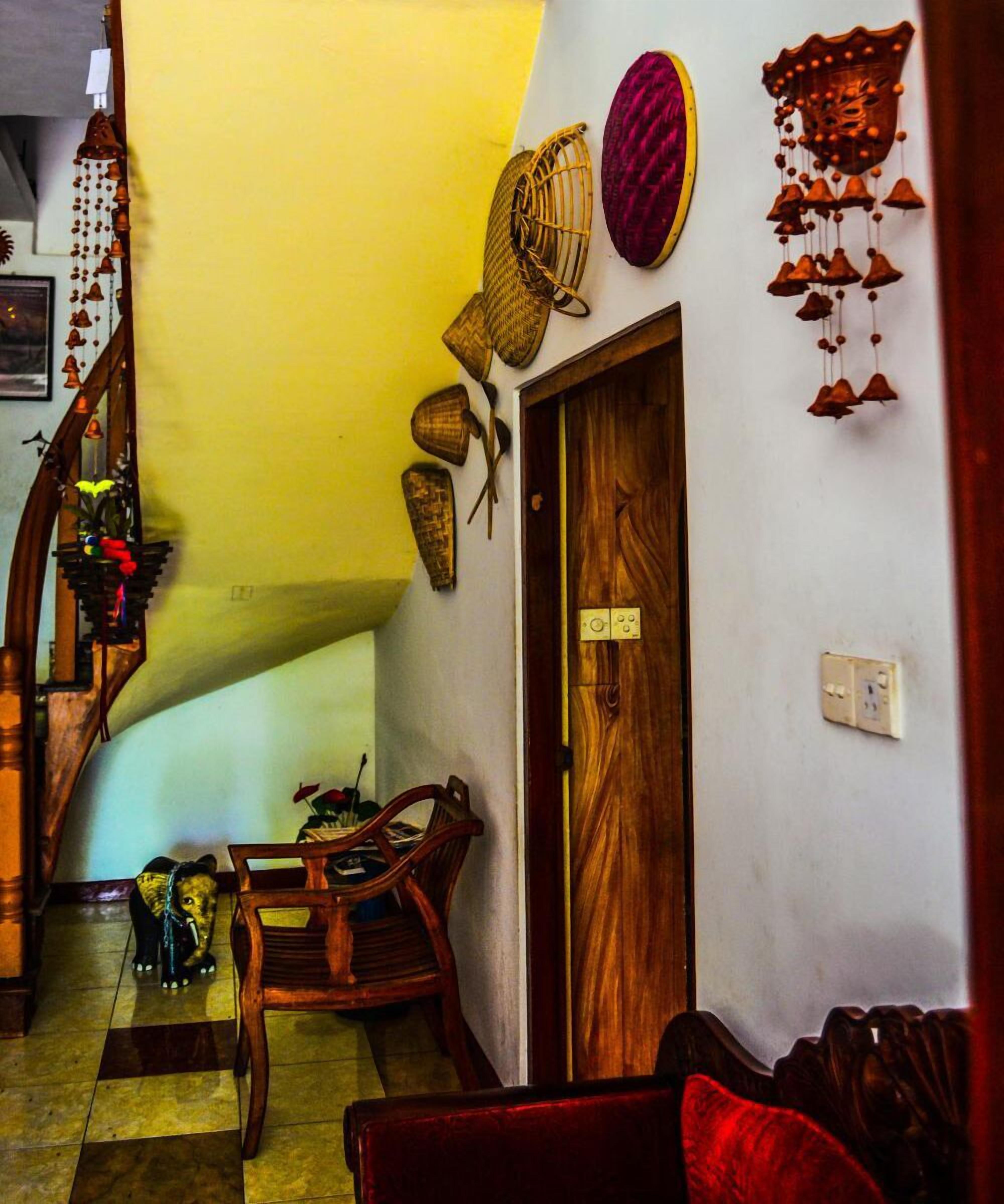 A staircase leading to a landing with a wooden door, a wooden chair, and a small elephant figurine on the floor.