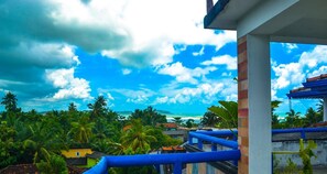 A balcony with a view of a tropical landscape, including palm trees and a beach. - Castle Bay Resort (Weligama)