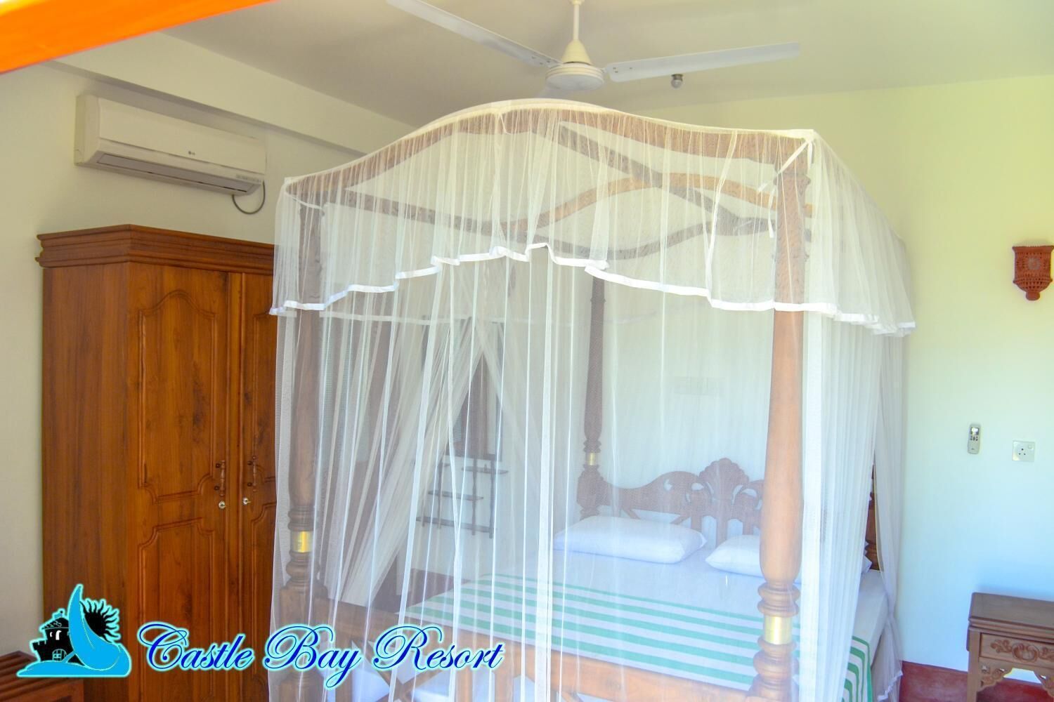 Un dormitorio con cama con dosel, un armario de madera y un ventilador de techo.