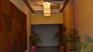 A reception area with a chandelier, two potted plants, and a door labeled "RECEPTION". - Eagle Palace Hotel (Nakuru)