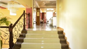 A grand staircase with a polished marble finish, leading to a room with a large mirror and a chandelier. - Eagle Palace Hotel (Nakuru)