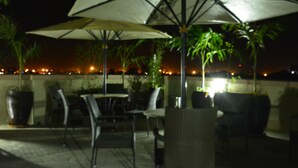 An outdoor seating area with umbrellas and chairs, overlooking a cityscape at night. - Eagle Palace Hotel (Nakuru)