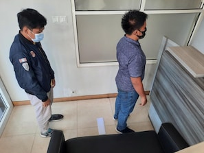 Due uomini in una stanza con una reception, una finestra e una porta.