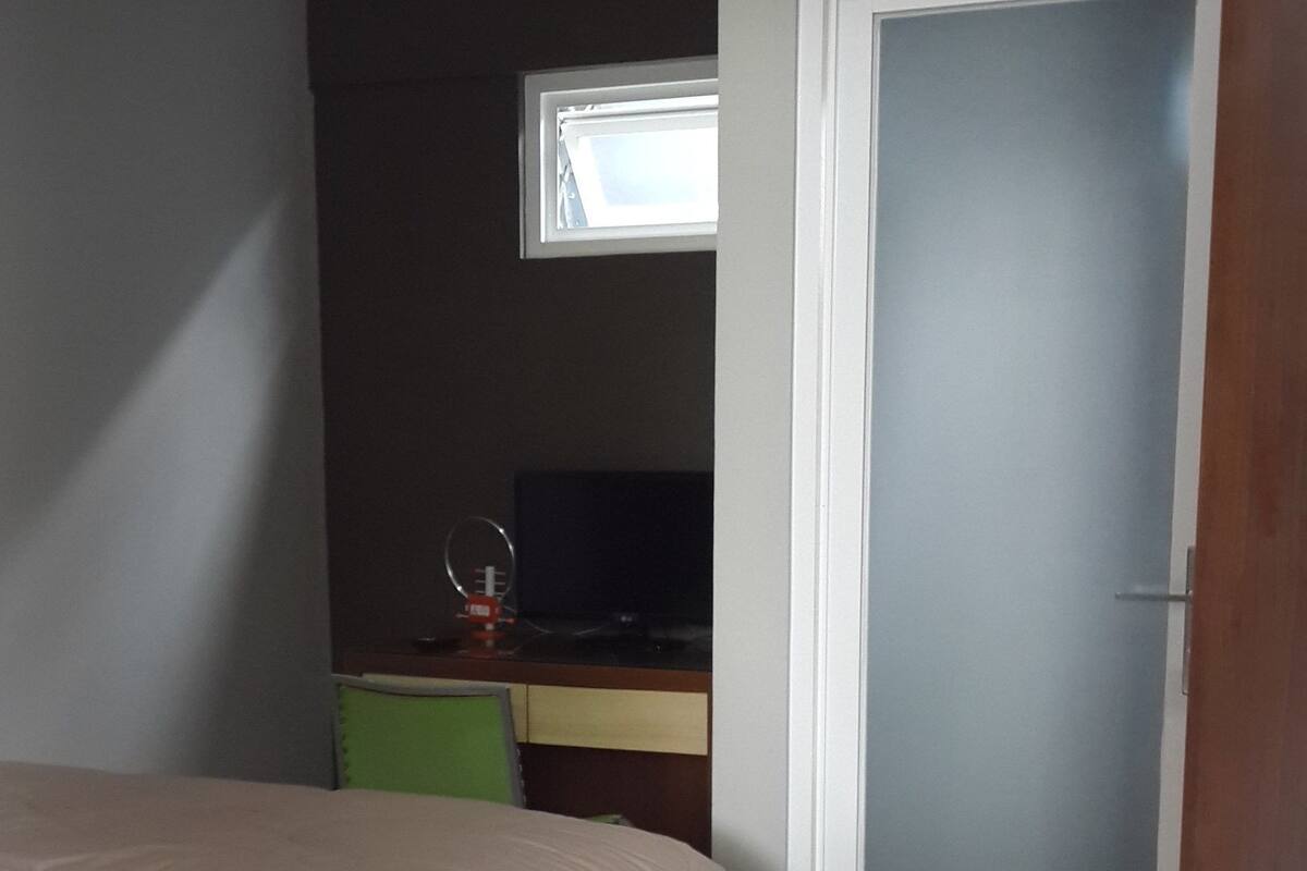A bedroom with a bed, a desk, and a door.
