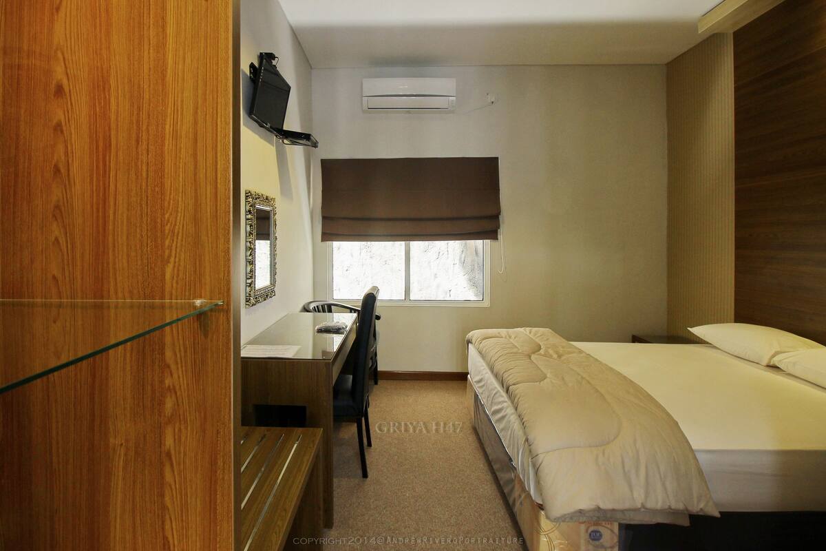 A compact hotel room with a bed, a desk, and a chair.