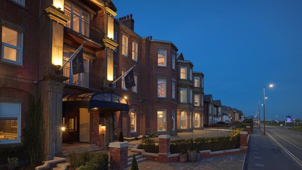 A row of brick townhouses with multiple stories, large windows, and a well-lit entrance. - Clifton Arms Hotel (Lytham St. Anne's)