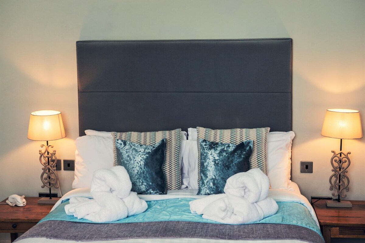 A hotel room with a large bed, two bedside lamps, and a decorative wall.