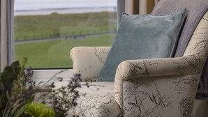 A chair with a map pattern, a view of a body of water, and a curtain. - Clifton Arms Hotel (Lytham St. Anne's)