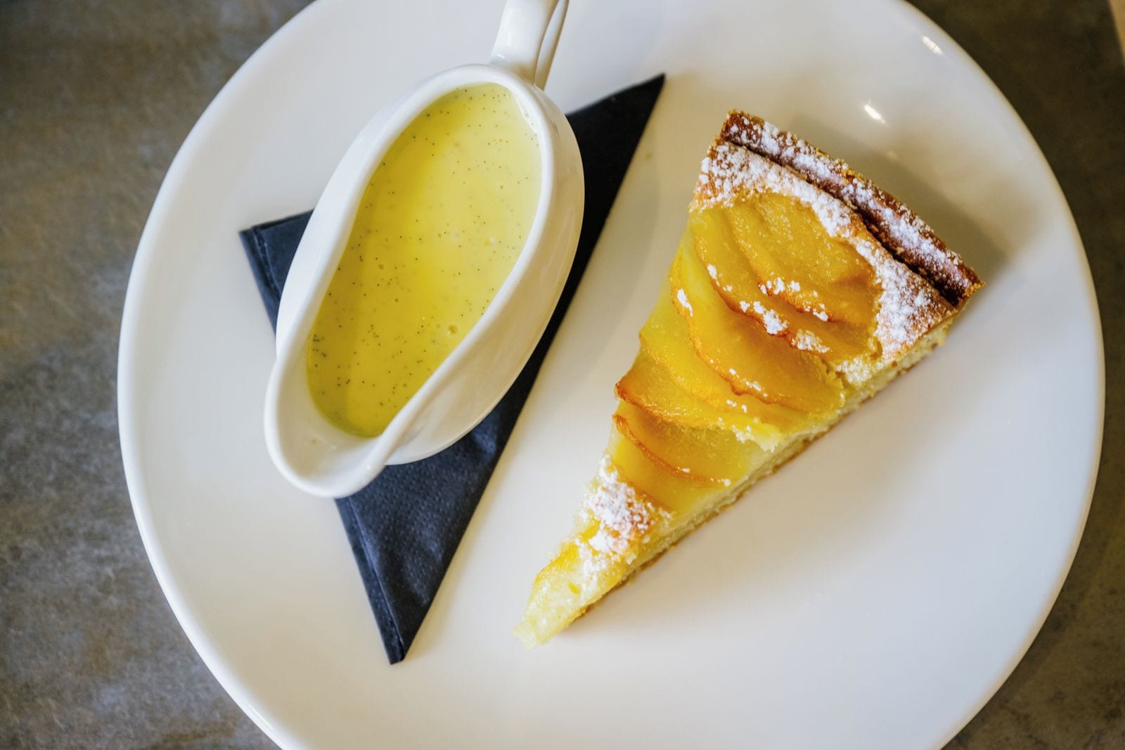 A slice of pie with a dusting of powdered sugar on a white plate.