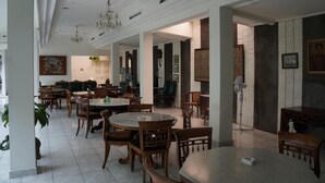 Un comedor amplio con mesas y sillas redondas, una araña y una chimenea.