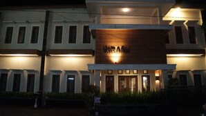 Un hotel moderno con un llamativo letrero de “KRAMA” en la fachada, múltiples ventanas y una entrada bien iluminada.