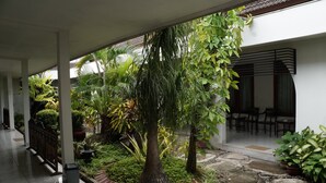 Un espacio al aire libre cubierto con un sendero de piedra, plantas en macetas y una zona de estar con sillas.