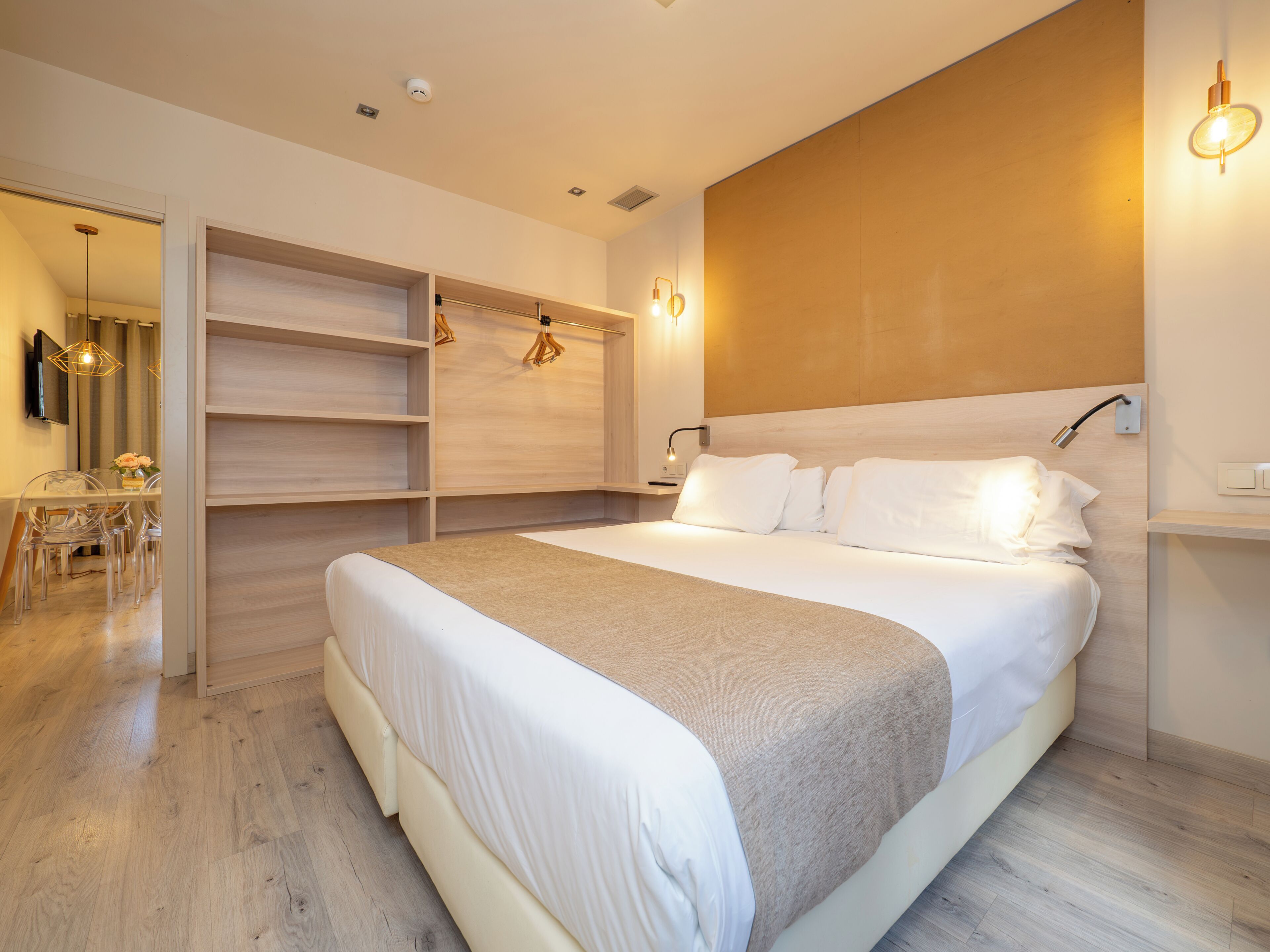 Un dormitorio moderno con una cama grande, estanterías empotradas, un escritorio y una zona de comedor.