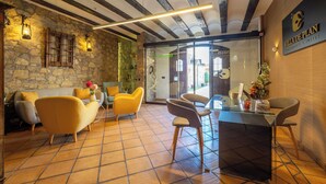A reception area with a stone wall, wooden beams, a reception desk, and seating. - Apartamentos Villa de Plan (Plan)