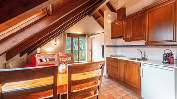 A kitchen with wooden cabinets, a dining table with chairs, and a view of the outdoors through a window.
