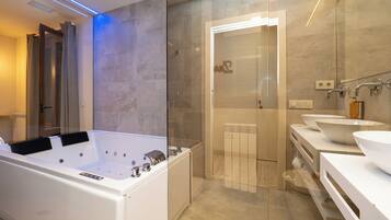 A modern bathroom with a large bathtub, two sinks, and a glass shower enclosure.