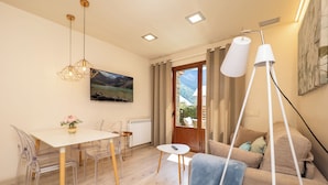 A modern living room with a dining area, a sofa, a coffee table, and a painting on the wall. - Apartamentos Villa de Plan (Plan)