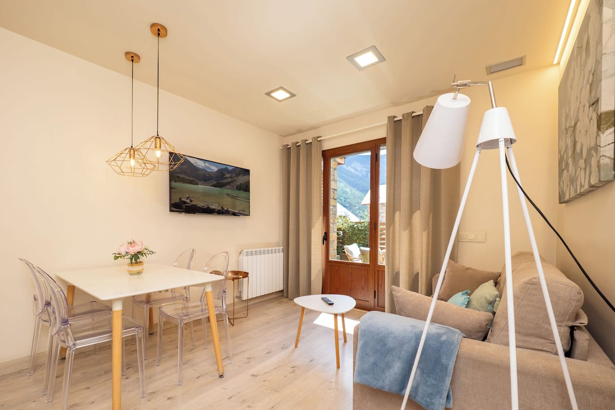 A modern living room with a dining area, a sofa, a coffee table, and a painting on the wall.