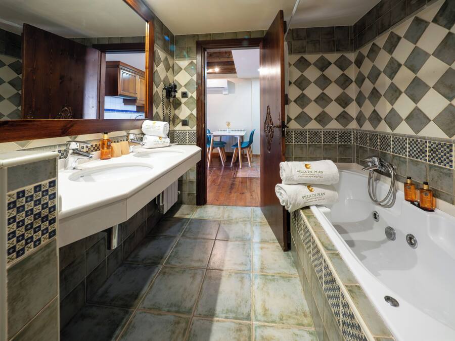 Un baño con dos lavabos, una bañera y una ducha.