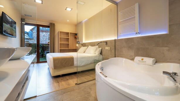 A modern bathroom with a bathtub, a large mirror, and a glass-enclosed balcony. - Apartamentos Villa de Plan (Plan)